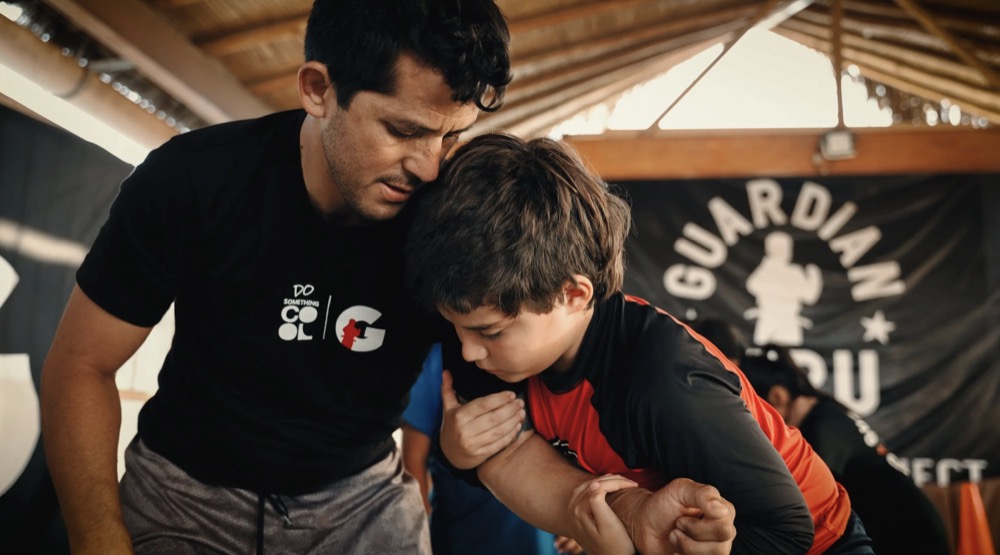 A coach working with a young student at the Guardian Peru jiu-jitsu academy in Mancora