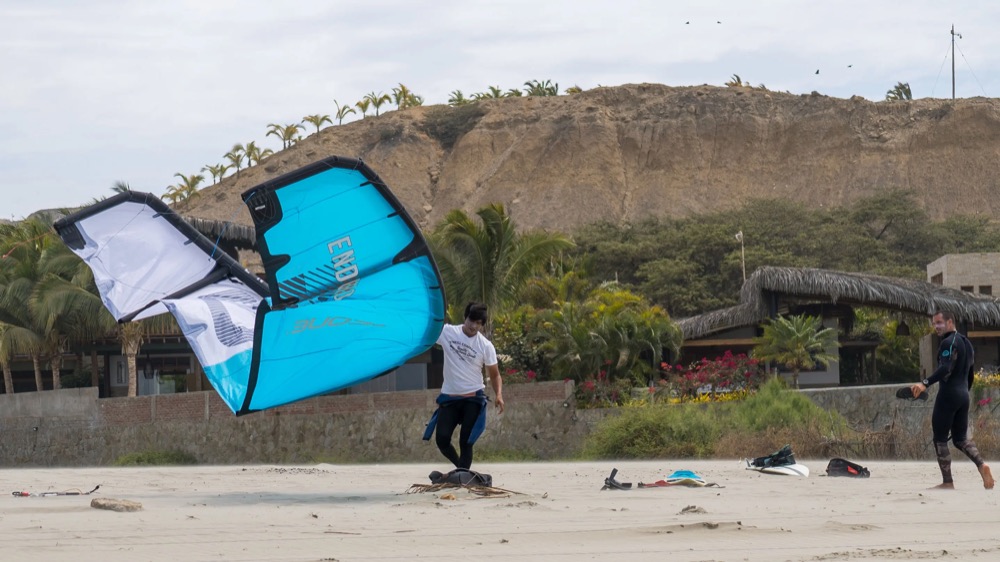 A kitesurfer coming in to the beach at Mancora with the cliffs behind