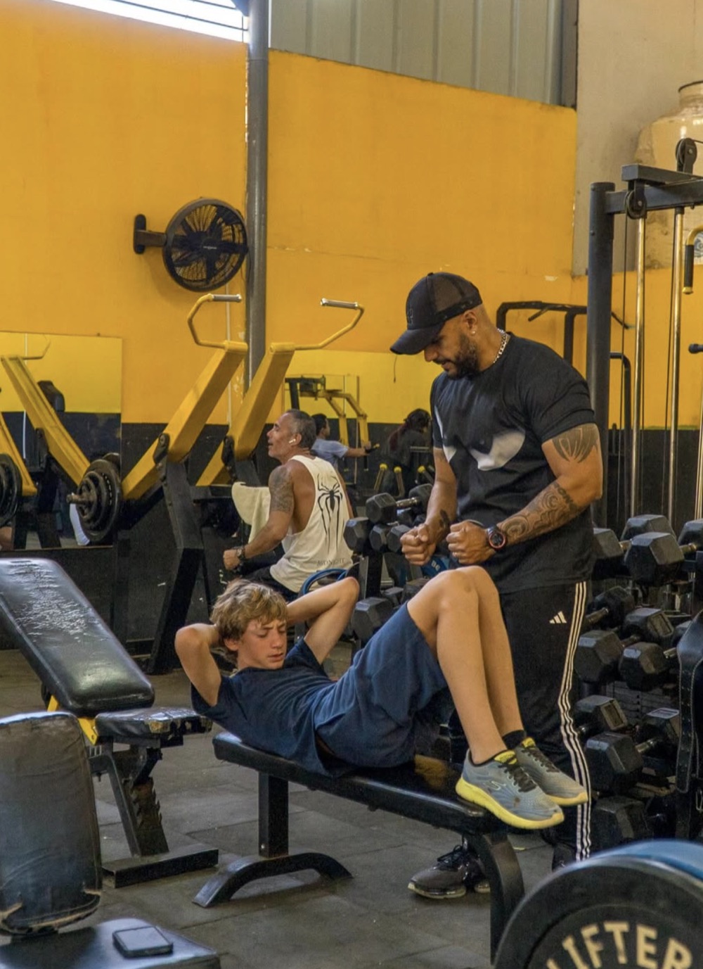A trainer spotting a young lifter at Samana Gym in Mancora