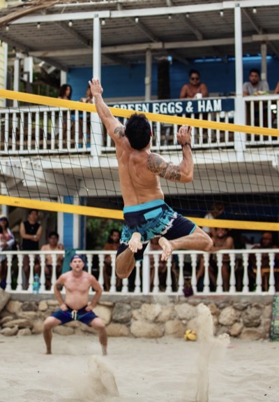A player rising to spike at the net on the beach in Mancora